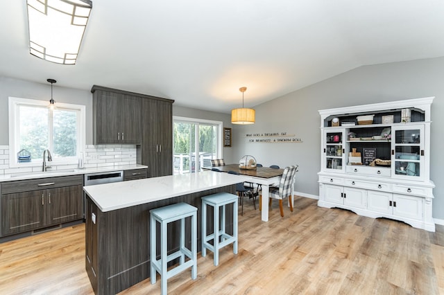2 Lillie Ln SE, Pine Island, MN 55963 - kitchen featuring dark brown cabinets, light wood finished floors, light countertops, a breakfast bar, and backsplash
