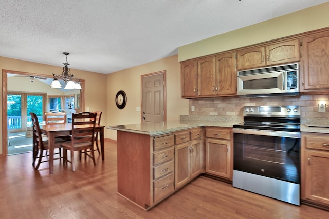 6 Pleasant View Ln, Circle Pines, MN 55014 - kitchen featuring appliances with stainless steel finishes, a peninsula, light wood finished floors, tasteful backsplash, and a textured ceiling