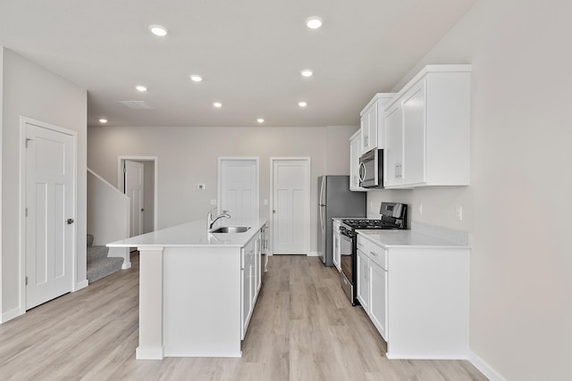 39730 Fallbrook Ave, North Branch, MN 55056 - kitchen with appliances with stainless steel finishes, light wood-type flooring, a center island with sink, white cabinetry, and light countertops