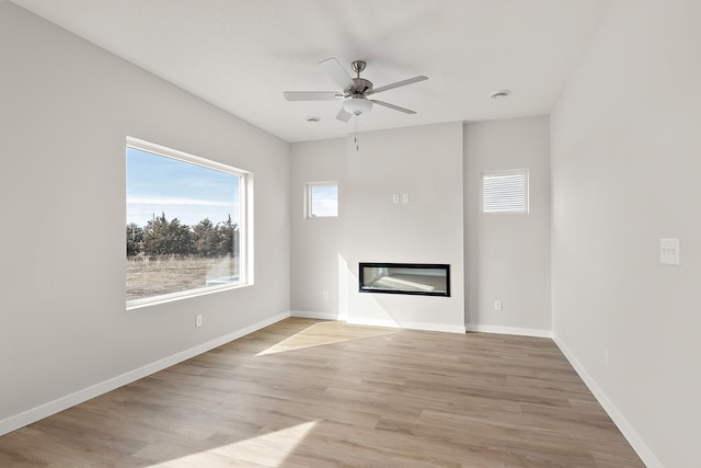 39730 Fallbrook Ave, North Branch, MN 55056 - unfurnished living room featuring a glass covered fireplace, ceiling fan, and light wood-type flooring