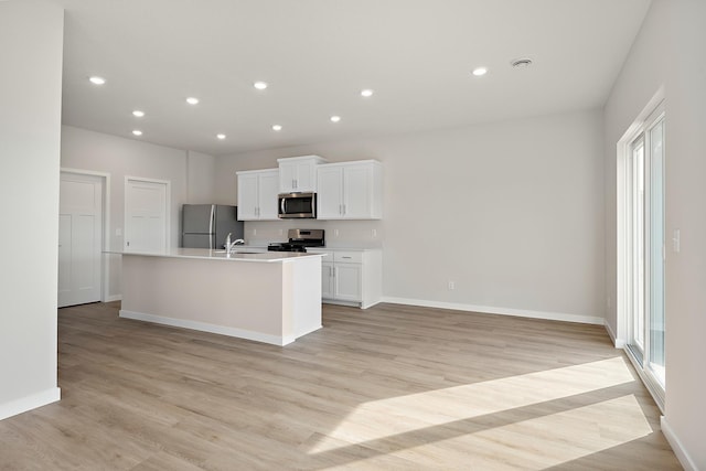 39730 Fallbrook Ave, North Branch, MN 55056 - kitchen featuring appliances with stainless steel finishes, white cabinets, an island with sink, light wood finished floors, and recessed lighting