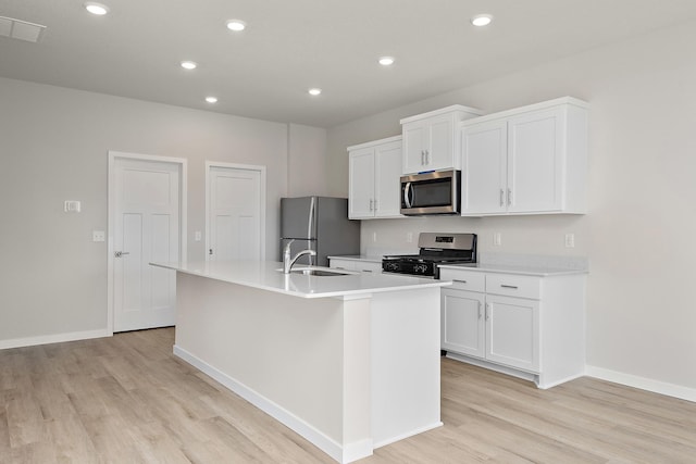 39730 Fallbrook Ave, North Branch, MN 55056 - kitchen featuring stainless steel appliances, light wood finished floors, a kitchen island with sink, white cabinetry, and recessed lighting