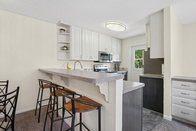 13525 Zenith Ln, Eden Prairie, MN 55346 - kitchen featuring appliances with stainless steel finishes, a kitchen breakfast bar, a peninsula, open shelves, and white cabinetry