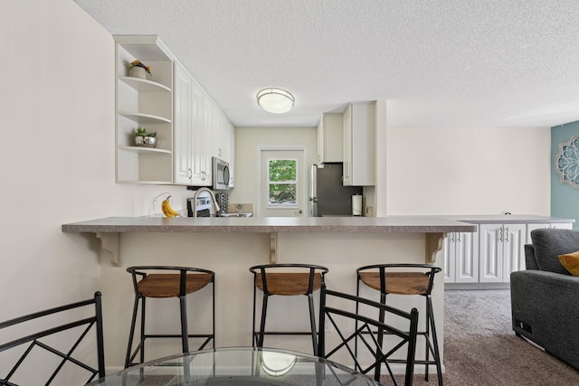 13525 Zenith Ln, Eden Prairie, MN 55346 - kitchen featuring stainless steel appliances, open shelves, a textured ceiling, a peninsula, and a kitchen breakfast bar