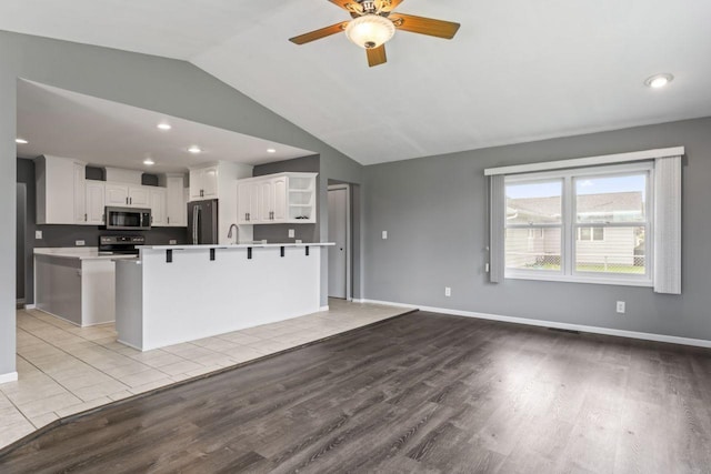 2100 10th St SW, Austin, MN 55912 - kitchen featuring stainless steel appliances, light wood-style flooring, open shelves, a ceiling fan, and lofted ceiling