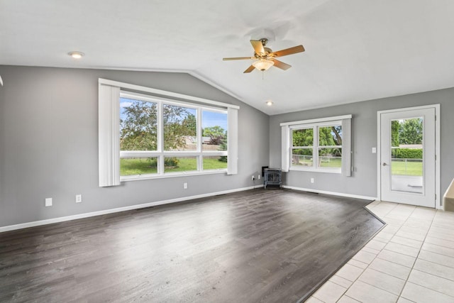 2100 10th St SW, Austin, MN 55912 - unfurnished living room with ceiling fan, vaulted ceiling, a wood stove, and wood finished floors