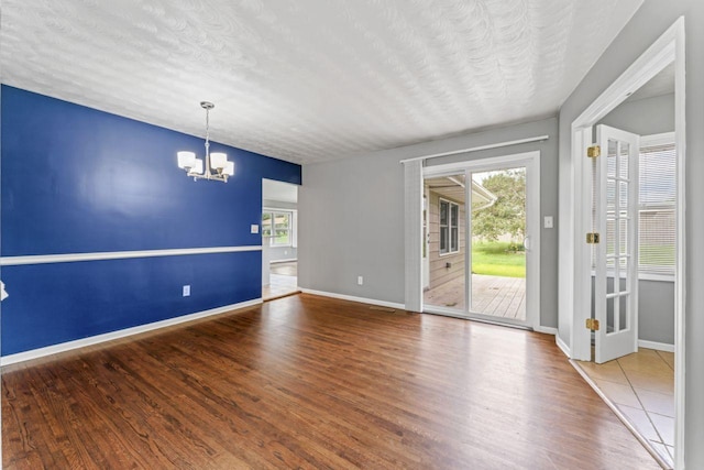 2100 10th St SW, Austin, MN 55912 - spare room with healthy amount of natural light, a chandelier, wood finished floors, and a textured ceiling
