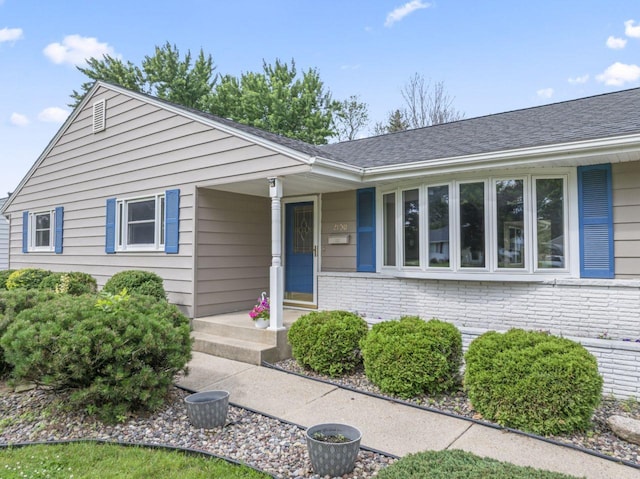 2100 10th St SW, Austin, MN 55912 - view of front of house with brick siding, a porch, and roof with shingles