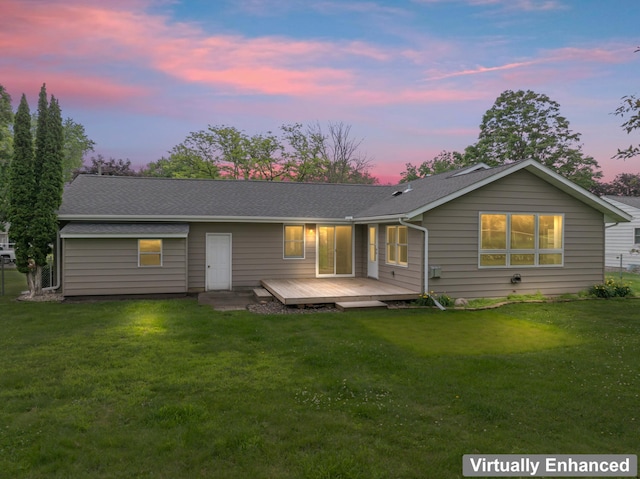2100 10th St SW, Austin, MN 55912 - back of property at dusk featuring a deck, a lawn, and a shingled roof