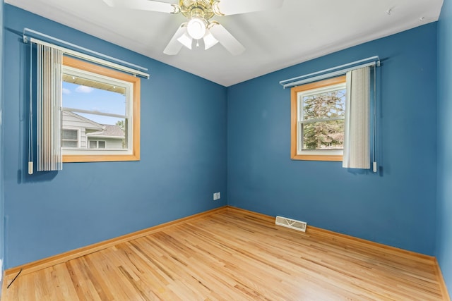 2100 10th St SW, Austin, MN 55912 - unfurnished room featuring healthy amount of natural light, wood finished floors, and a ceiling fan