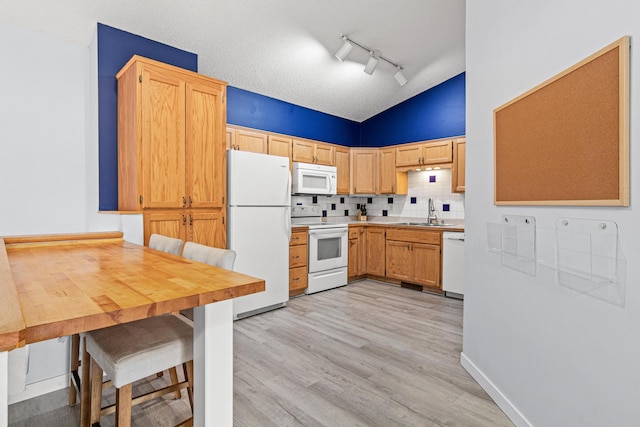 940 14th Ln SE, Cambridge, MN 55008 - kitchen featuring white appliances, lofted ceiling, light wood-style flooring, rail lighting, and decorative backsplash