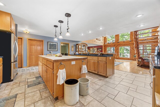 36773 Rose Lake Rd, Hobart Twp, MN 56544 - kitchen with freestanding refrigerator, a center island with sink, recessed lighting, stone tile flooring, and pendant lighting