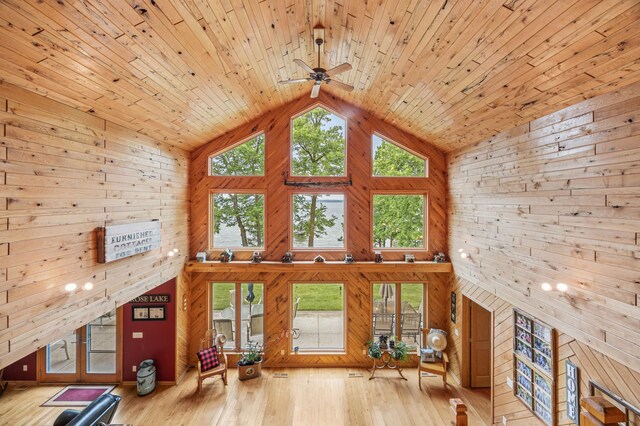 36773 Rose Lake Rd, Hobart Twp, MN 56544 - unfurnished living room featuring wood walls, high vaulted ceiling, wood finished floors, a ceiling fan, and a fireplace