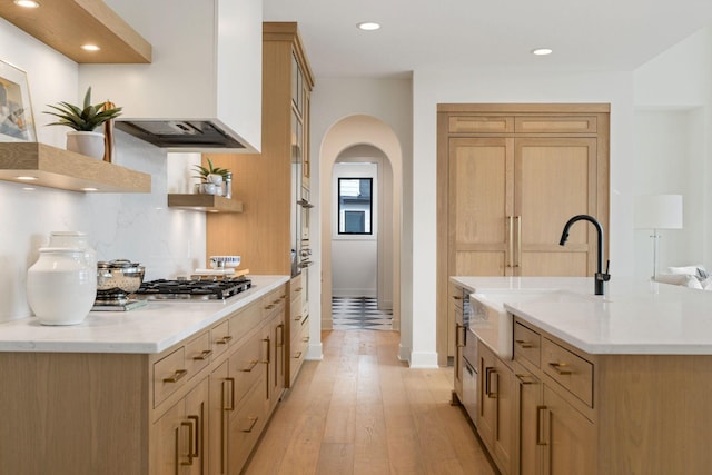 5250 Polaris Ln N, Plymouth, MN 55446 - kitchen featuring open shelves, range hood, stainless steel gas cooktop, arched walkways, and light wood-style floors