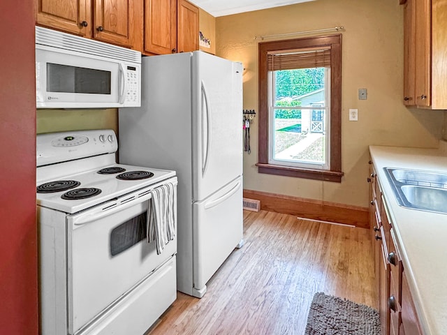 306 Jefferson St, Minneota, MN 56264 - kitchen featuring white appliances, light wood-type flooring, brown cabinetry, and light countertops