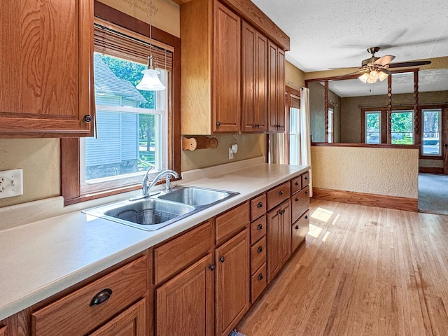 306 Jefferson St, Minneota, MN 56264 - kitchen featuring brown cabinets, light wood-style flooring, light countertops, a ceiling fan, and a textured ceiling