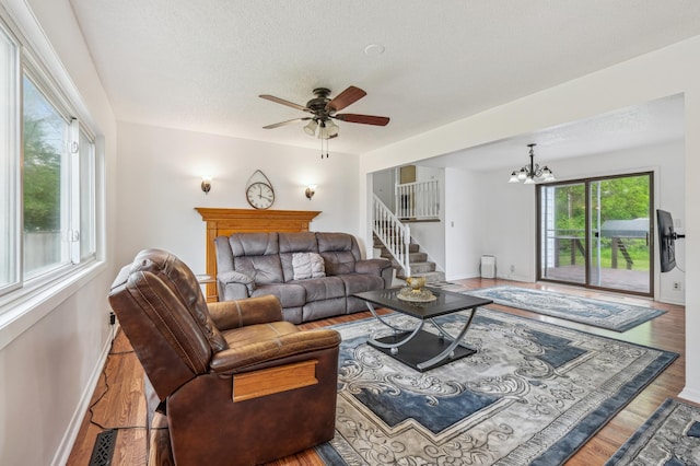 2715 90th Ln NE, Blaine, MN 55449 - living room featuring wood finished floors, a textured ceiling, ceiling fan, stairs, and a chandelier