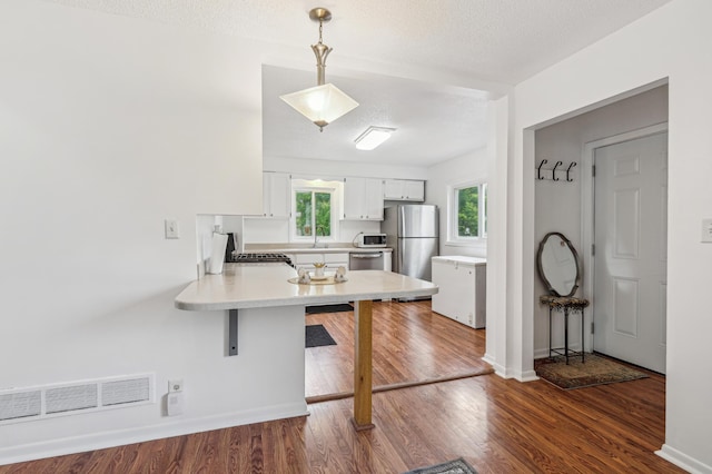 2715 90th Ln NE, Blaine, MN 55449 - kitchen with appliances with stainless steel finishes, a kitchen breakfast bar, a peninsula, light countertops, and white cabinetry