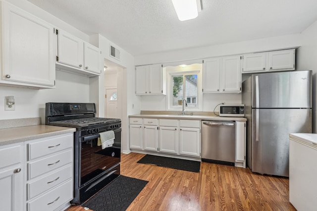 2715 90th Ln NE, Blaine, MN 55449 - kitchen featuring stainless steel appliances, white cabinetry, light countertops, and light wood-style floors