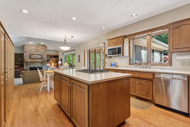 10910 38th Ave N, Plymouth, MN 55441 - kitchen featuring appliances with stainless steel finishes, a textured ceiling, light wood-type flooring, a center island, and light countertops