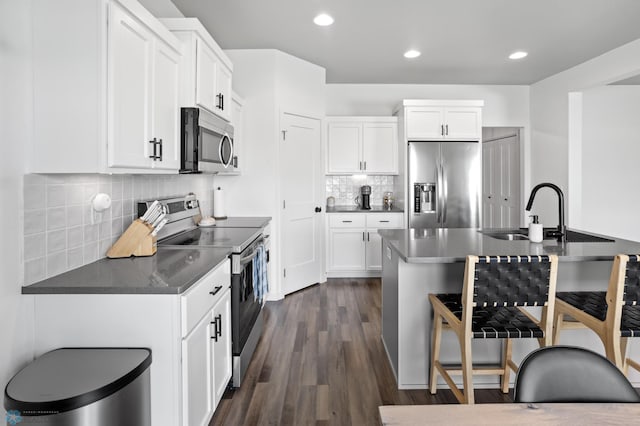 1030 Albert Dr W, West Fargo, ND 58078 - kitchen with stainless steel appliances, a breakfast bar area, decorative backsplash, dark wood-style floors, and recessed lighting