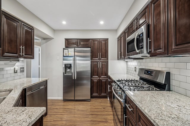 8 110th Ln NW, Coon Rapids, MN 55448 - kitchen with appliances with stainless steel finishes, tasteful backsplash, light stone counters, wood finished floors, and dark brown cabinetry