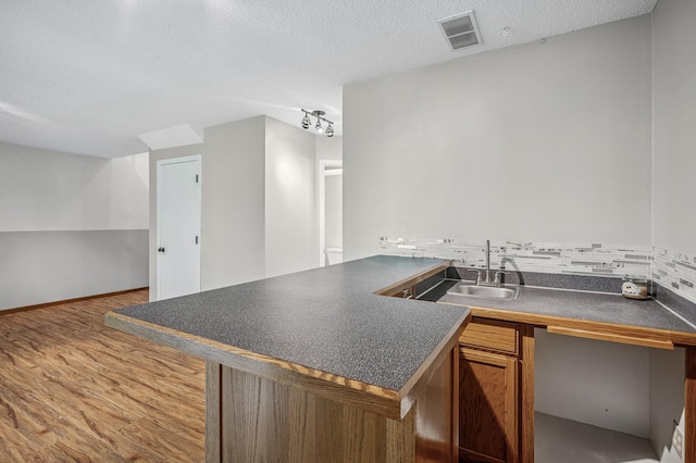8 110th Ln NW, Coon Rapids, MN 55448 - kitchen featuring dark countertops, a textured ceiling, wood finished floors, tasteful backsplash, and a peninsula