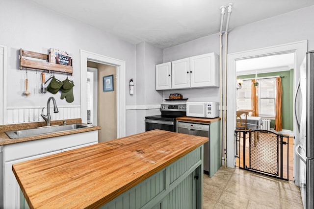 41 9th St, Cloquet, MN 55720 - kitchen featuring stainless steel appliances, butcher block countertops, white cabinetry, a center island, and green cabinets