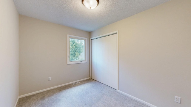 929 40th St NW, Rochester, MN 55901 - unfurnished bedroom with a closet, light colored carpet, and a textured ceiling