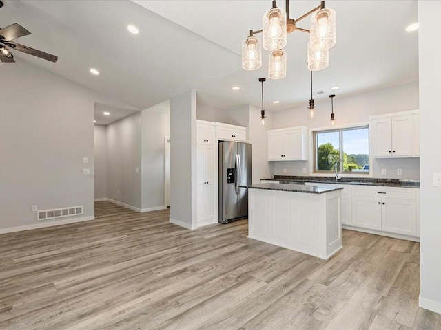 31418 Isabelle Dr, Pequot Lakes, MN 56472 - kitchen with stainless steel refrigerator with ice dispenser, dark countertops, light wood-style flooring, a ceiling fan, and white cabinetry