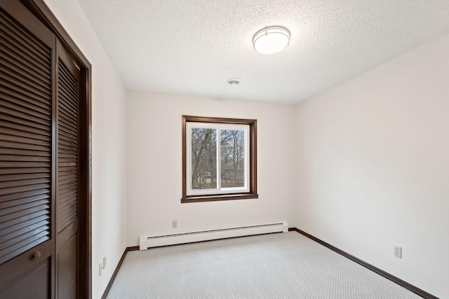 6485 46th Ave SE, Haven Twp, MN 56304 - unfurnished bedroom featuring a baseboard heating unit, carpet flooring, a closet, and a textured ceiling