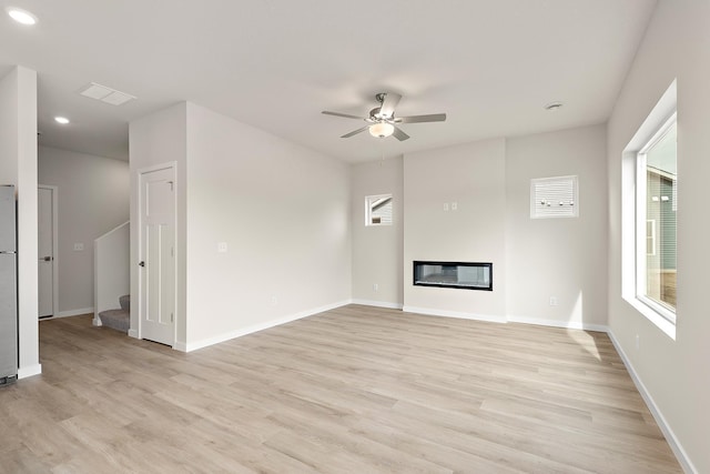 39746 Fallbrook Ave, North Branch, MN 55056 - unfurnished living room featuring ceiling fan, light wood finished floors, stairway, plenty of natural light, and recessed lighting