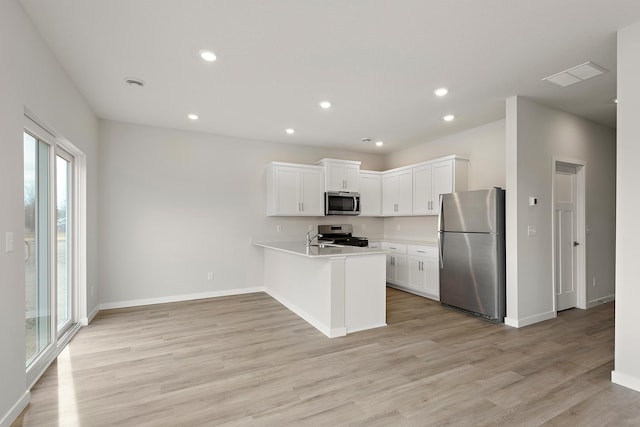 39746 Fallbrook Ave, North Branch, MN 55056 - kitchen with stainless steel appliances, a peninsula, light countertops, light wood-type flooring, and white cabinets