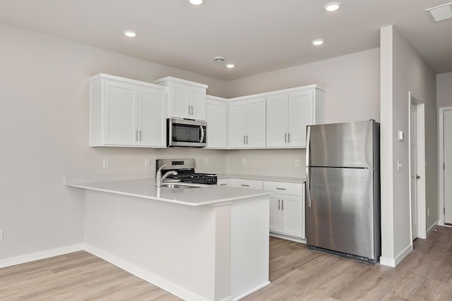 39746 Fallbrook Ave, North Branch, MN 55056 - kitchen featuring appliances with stainless steel finishes, light wood finished floors, light countertops, a peninsula, and recessed lighting