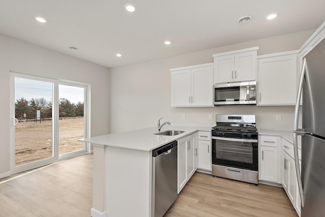 39746 Fallbrook Ave, North Branch, MN 55056 - kitchen featuring stainless steel appliances, a peninsula, light wood-type flooring, white cabinetry, and recessed lighting