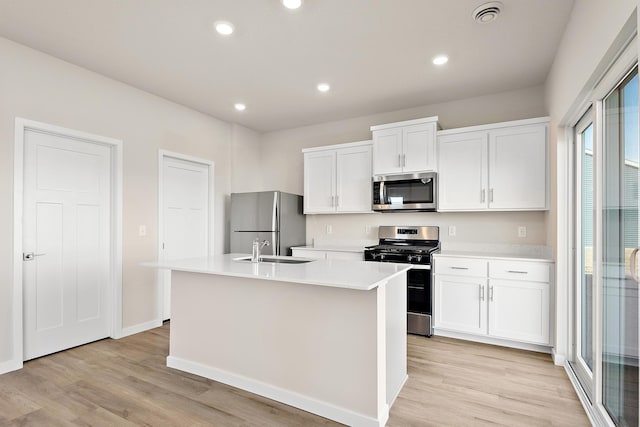 39743 Fallbrook Ave, North Branch, MN 55056 - kitchen with stainless steel appliances, an island with sink, light wood-style flooring, light countertops, and white cabinetry