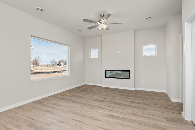 39743 Fallbrook Ave, North Branch, MN 55056 - unfurnished living room featuring light wood finished floors, a ceiling fan, and a glass covered fireplace