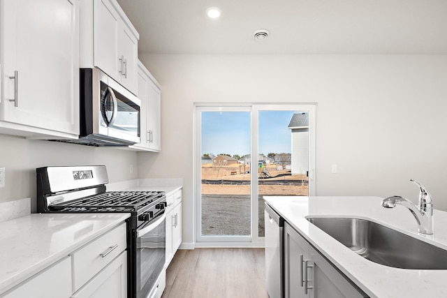 39743 Fallbrook Ave, North Branch, MN 55056 - kitchen with stainless steel appliances, light wood finished floors, light stone countertops, white cabinetry, and recessed lighting