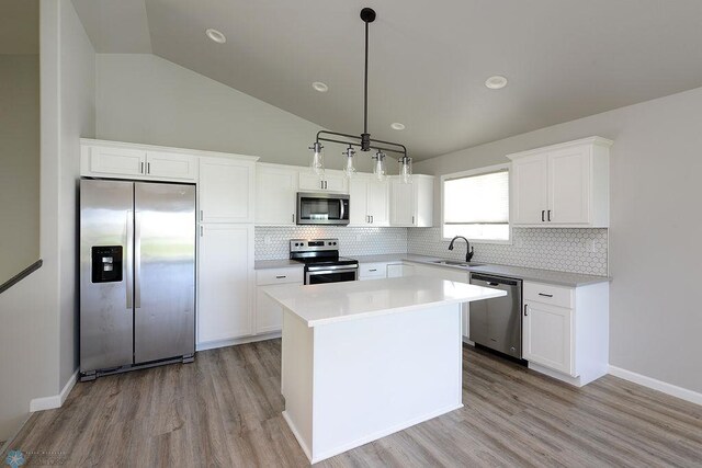 1170 Highland Ln W, West Fargo, ND 58078 - kitchen with stainless steel appliances, lofted ceiling, light wood finished floors, white cabinets, and tasteful backsplash