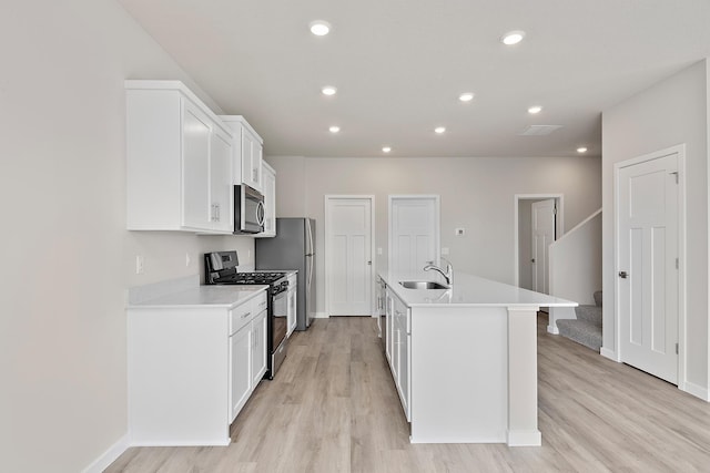 39726 Fallbrook Ave, North Branch, MN 55056 - kitchen with stainless steel appliances, light wood-style floors, white cabinetry, an island with sink, and recessed lighting