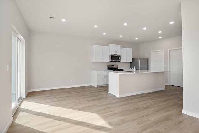 39726 Fallbrook Ave, North Branch, MN 55056 - kitchen featuring stainless steel appliances, a kitchen island with sink, white cabinetry, light wood finished floors, and light countertops