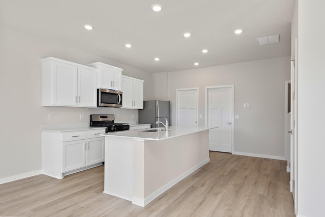 39726 Fallbrook Ave, North Branch, MN 55056 - kitchen with stainless steel appliances, a center island with sink, light wood-style floors, white cabinetry, and recessed lighting