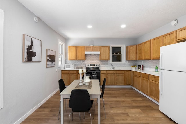 2804 Pillsbury Ave S, Minneapolis, MN 55408 - kitchen with white appliances, under cabinet range hood, light countertops, decorative backsplash, and recessed lighting