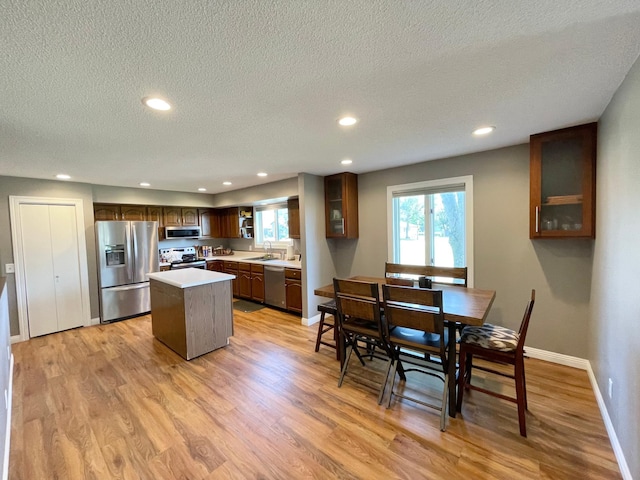 402 Range Rd, Springfield, MN 56087 - kitchen with stainless steel appliances, a kitchen island, a textured ceiling, light wood-style flooring, and glass insert cabinets