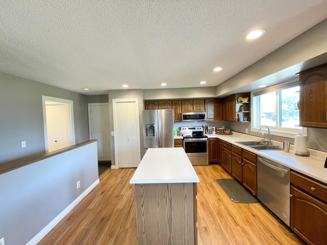 402 Range Rd, Springfield, MN 56087 - kitchen featuring appliances with stainless steel finishes, a center island, light wood-style floors, a textured ceiling, and light countertops