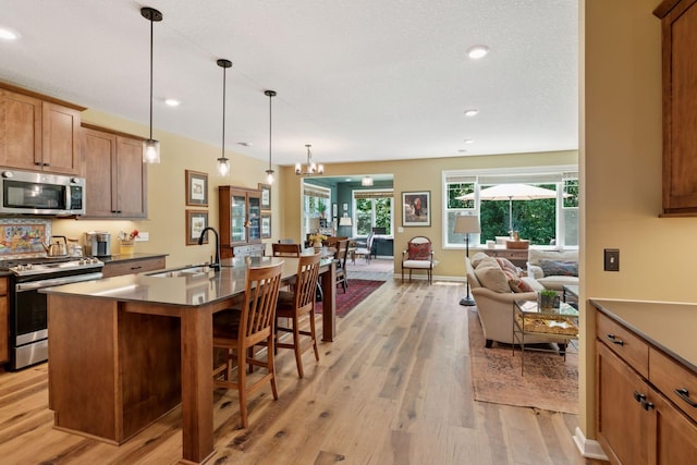 1101 Fabel Ln, Waconia, MN 55387 - kitchen with appliances with stainless steel finishes, light wood-type flooring, open floor plan, a breakfast bar area, and a kitchen island with sink