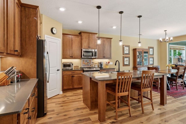 1101 Fabel Ln, Waconia, MN 55387 - kitchen featuring stainless steel appliances, brown cabinets, light wood-style floors, a breakfast bar, and recessed lighting