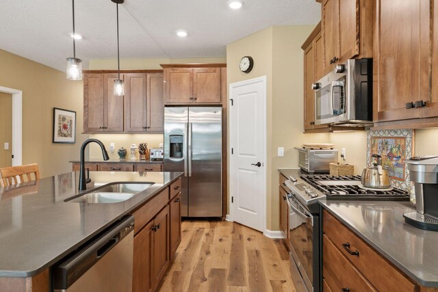 1101 Fabel Ln, Waconia, MN 55387 - kitchen featuring stainless steel appliances, brown cabinetry, light wood-type flooring, dark countertops, and recessed lighting