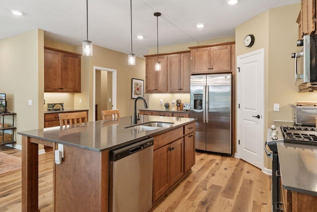 1101 Fabel Ln, Waconia, MN 55387 - kitchen featuring stainless steel appliances, light wood finished floors, dark countertops, a center island with sink, and hanging light fixtures