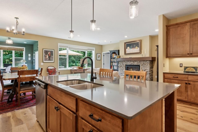 1101 Fabel Ln, Waconia, MN 55387 - kitchen with light wood-style flooring, brown cabinetry, a stone fireplace, dishwasher, and recessed lighting